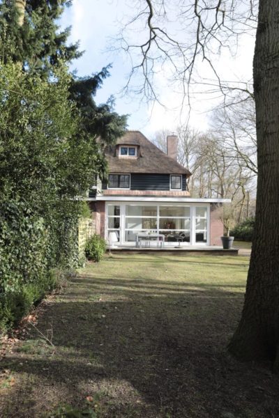 Moderne woninguitbreiding met grote raampartijen en panoramisch uitzicht op de groene tuin.