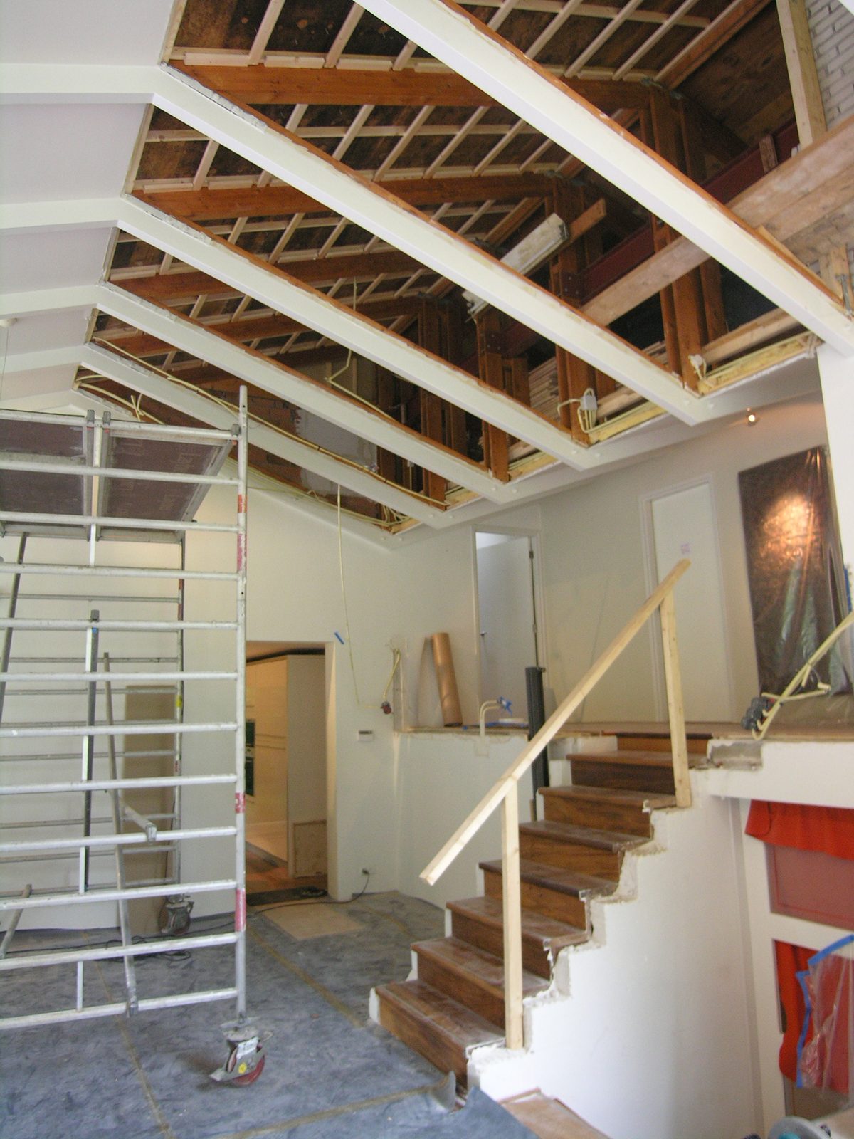 Renovatie van een villa met zichtbare houten dakconstructie, trap en steiger in de woonruimte.