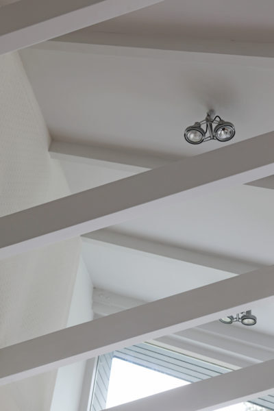 Strak wit plafond met zichtbare balkenconstructie en moderne inbouwspots in een villa.