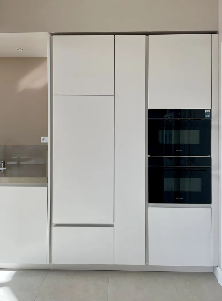 Strakke witte Cesar Maxima 2.2 kastenwand met geïntegreerde ovens in een minimalistische keukenopstelling.