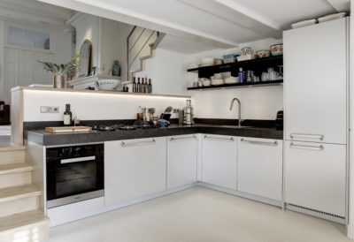 Lichte hoekkeuken met aluminium fronten en donker stenen werkblad in een Amsterdams appartement.