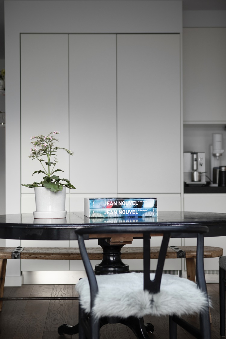 Zwarte ronde tafel met boeken en plant voor strakke witte kastenwand in vernieuwd interieur.