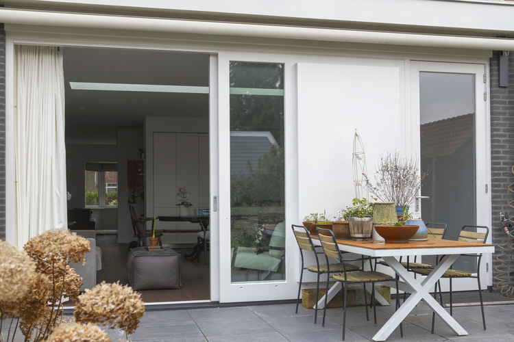 Grote glazen schuifpui die de vernieuwde begane grond verbindt met het terras en de tuin.
