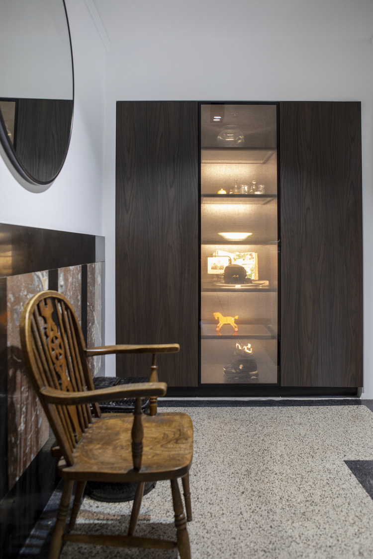Maatwerk donkerhouten wandkast met verlichte vitrine in een stijlvol vernieuwd interieur.