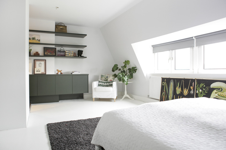 Lichte slaapkamer met op maat gemaakt groen dressoir, wandplanken en een comfortabele fauteuil.