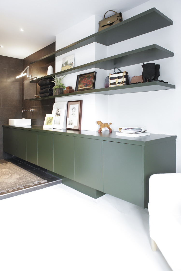Maatwerk groen dressoir met zwevende wandplanken en decoratie in een vernieuwd interieur.